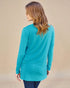 Woman wearing a turquoise long-sleeve top against a beige background