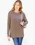 A woman modeling a long-sleeve crewneck tunic top in taupe brown, paired with blue jeans and carrying a light-colored shoulder bag against a plain white background.
