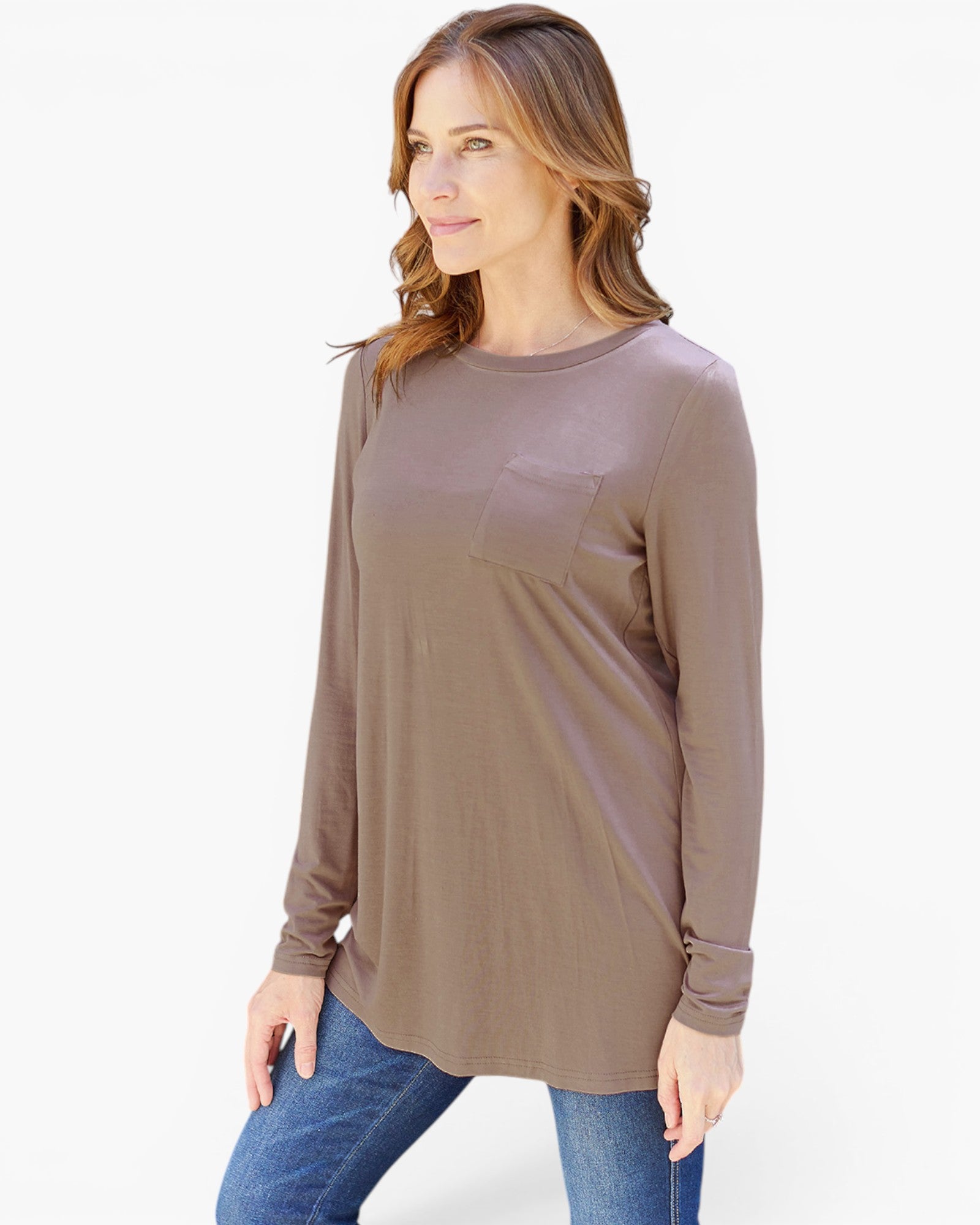 A woman wearing a taupe brown long-sleeve tunic top with a chest pocket, paired with blue jeans, photographed against a clean white background.