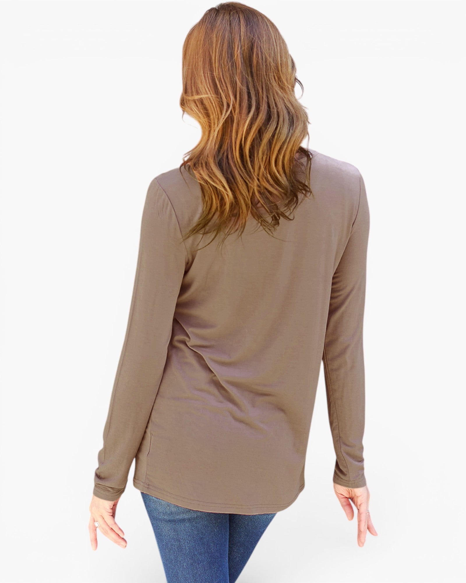 A woman viewed from the back wearing a taupe brown long-sleeve top and blue jeans against a plain white background.