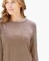 A woman wearing a long-sleeve crewneck top in a muted taupe-brown color, featuring a chest pocket, shown against a plain white background.