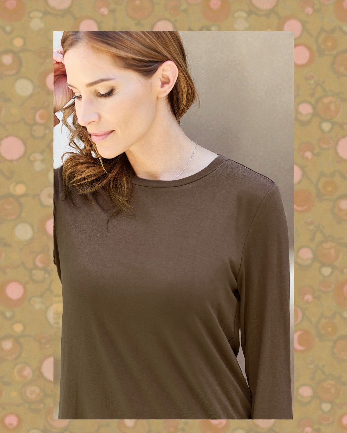 Woman wearing a brown long-sleeve top against a patterned background