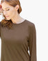 A woman wearing a plain brown long-sleeve crewneck top, shown from the chest up against a light gray background.