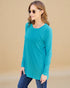 Woman wearing a teal long-sleeve top against a beige background