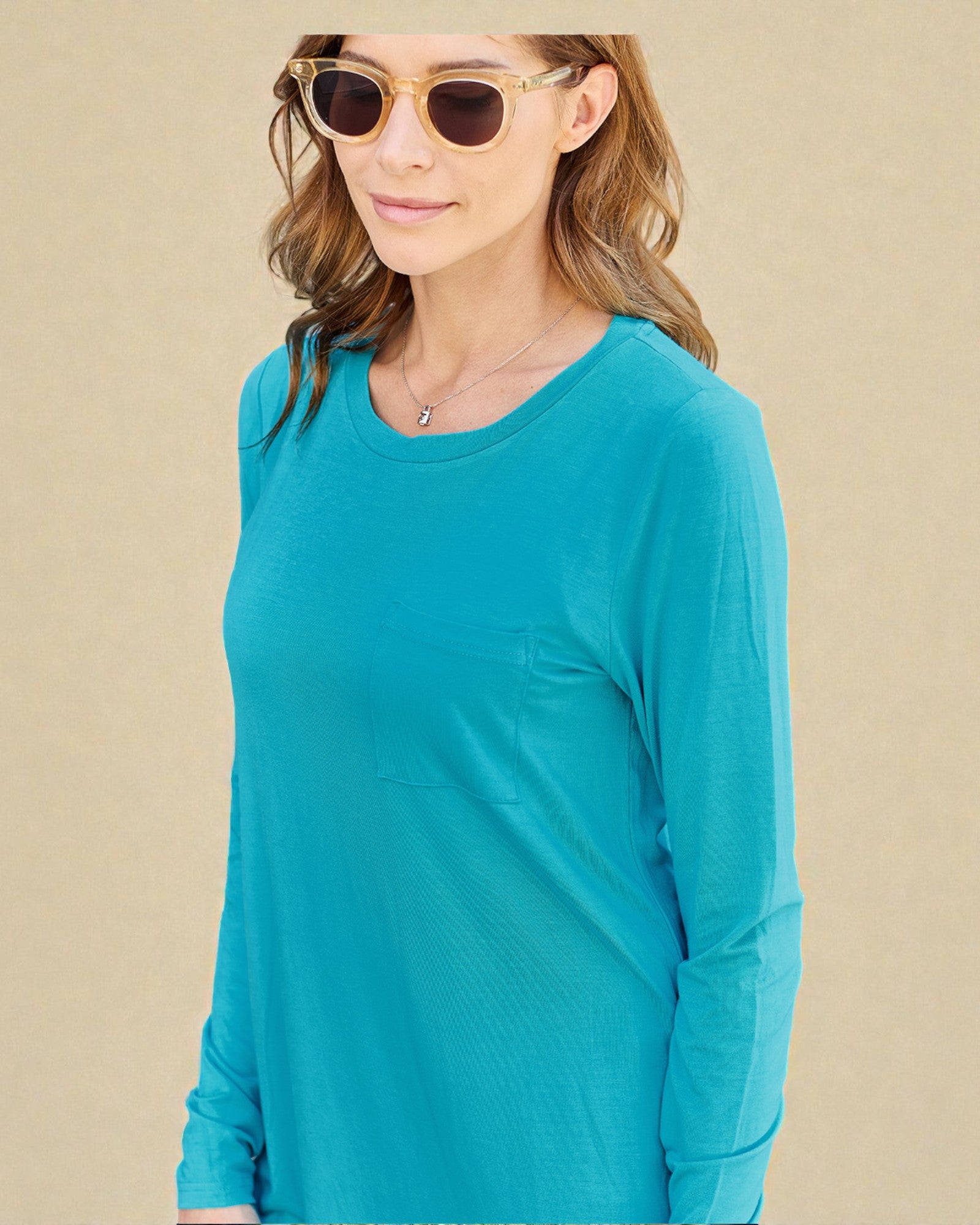 Woman wearing a teal long-sleeve shirt against a beige background