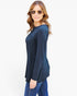 A woman modeling a dark navy blue long-sleeve top with a chest pocket, paired with blue jeans, against a plain white background.
