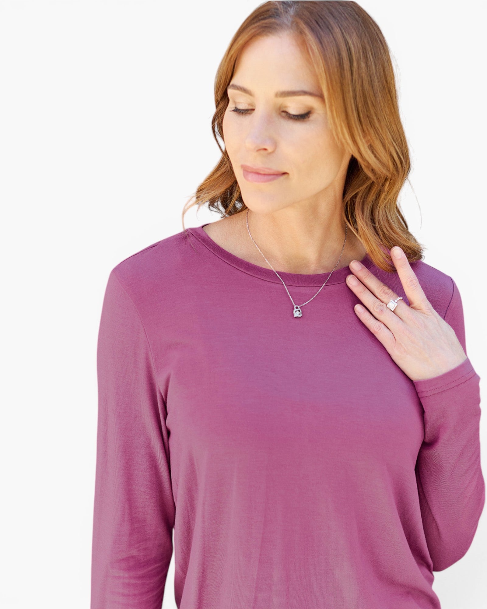 A woman wearing a dusty rose long-sleeve crewneck top, shown from the chest up against a plain white background.