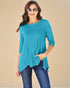 Woman wearing a teal top and blue jeans on a beige background