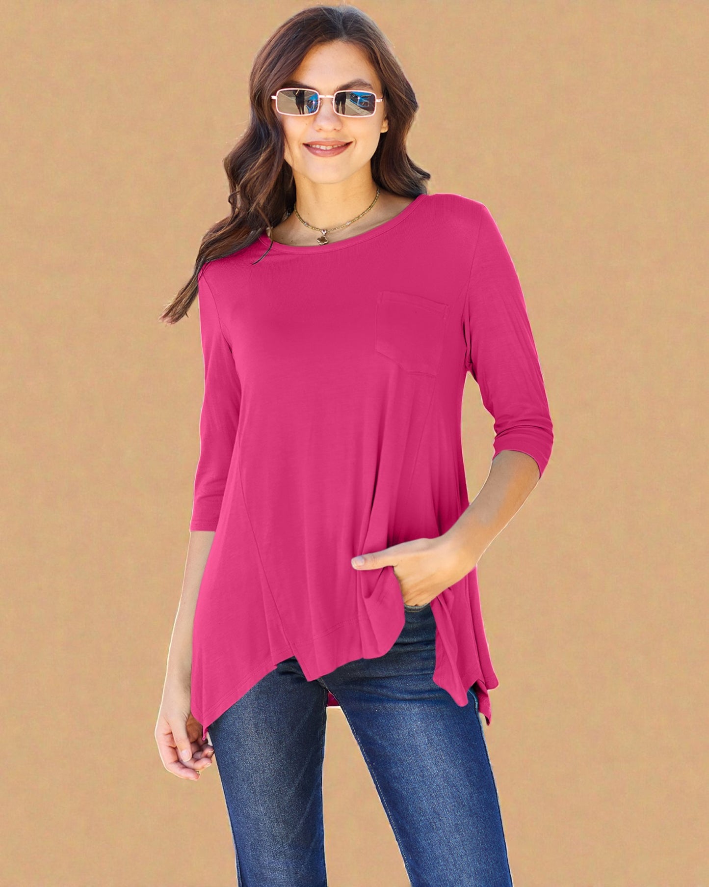 Woman wearing a bright pink top and blue jeans on a beige background