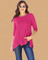 Woman wearing a bright pink top and blue jeans on a beige background