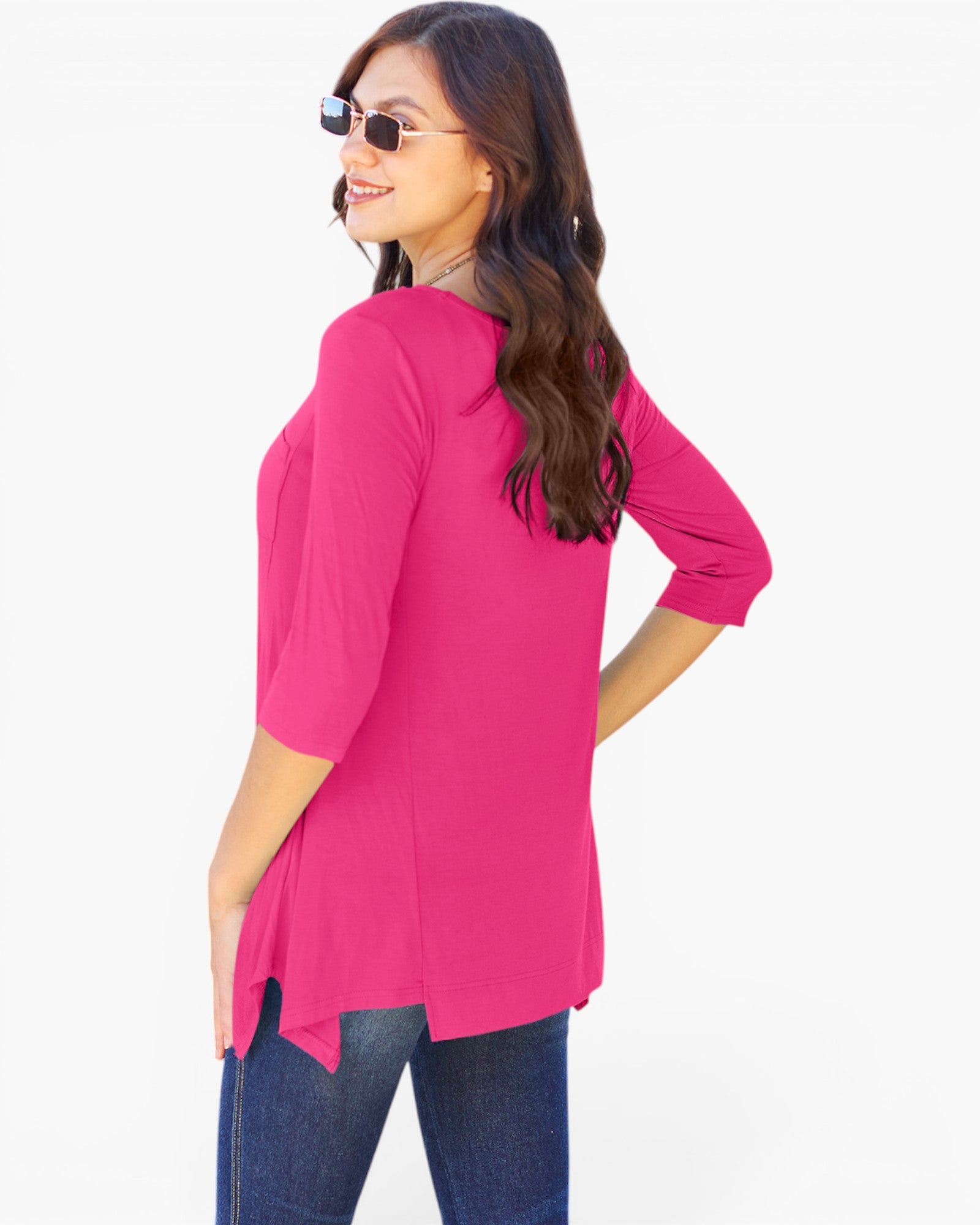A woman wearing a bright pink three-quarter sleeve tunic top and dark blue jeans, photographed from the back against a plain white background.