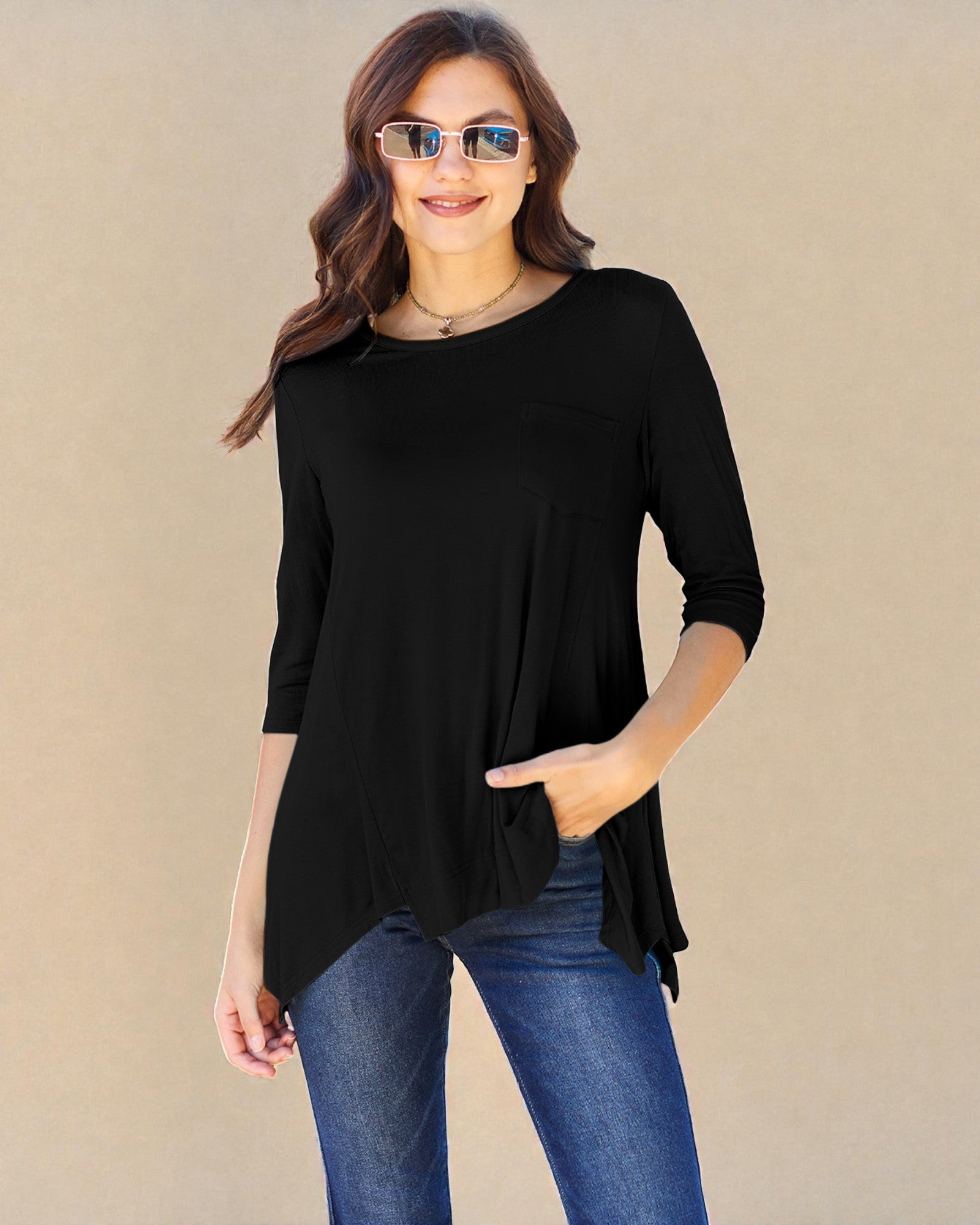 Woman wearing a black top and blue jeans with sunglasses on a beige background