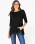 A woman modeling a black three-quarter sleeve tunic top with a high-low hem and side pockets, paired with blue jeans, against a plain white background.
