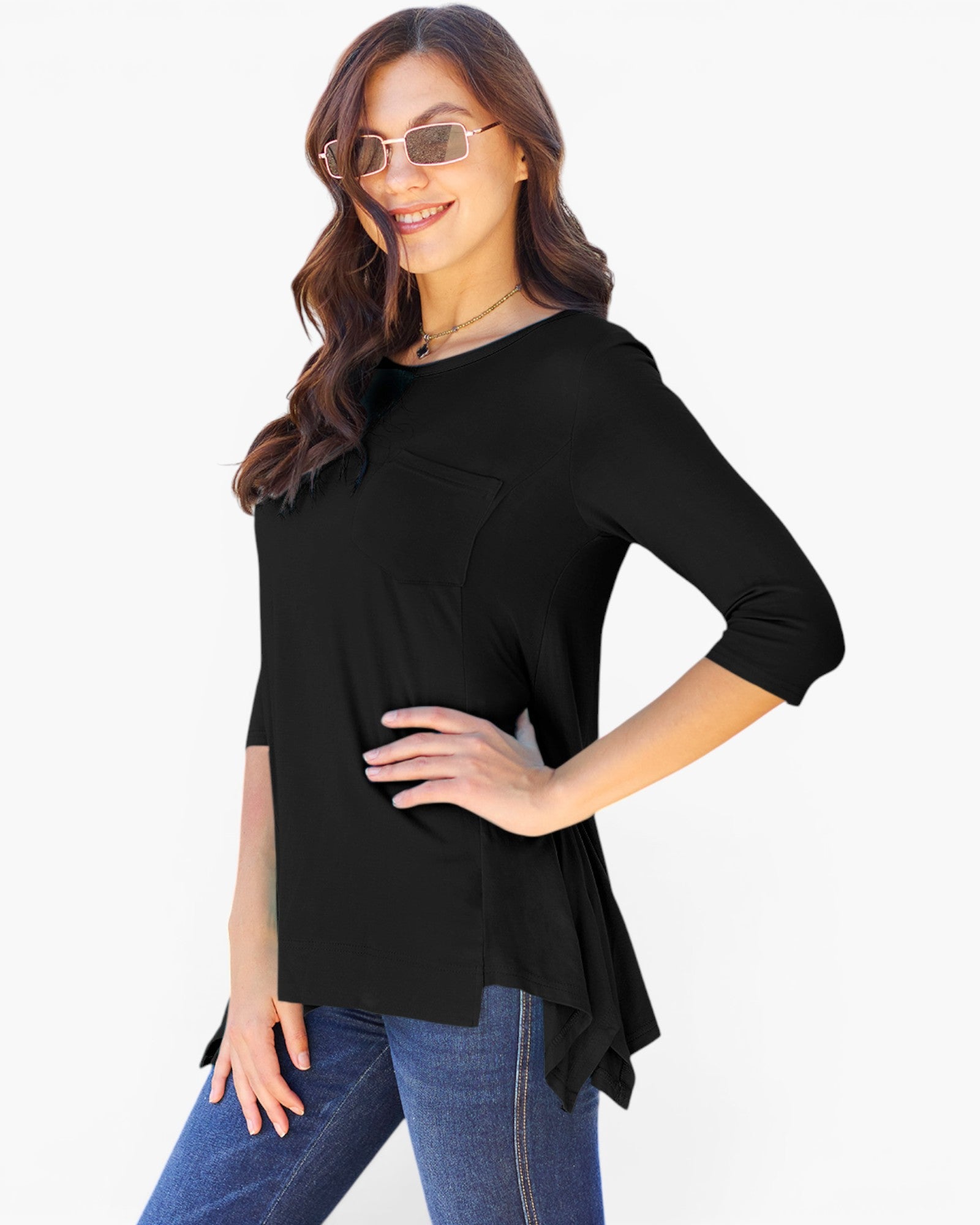 A woman modeling a black three-quarter sleeve top with a chest pocket, paired with blue jeans, against a plain white background.