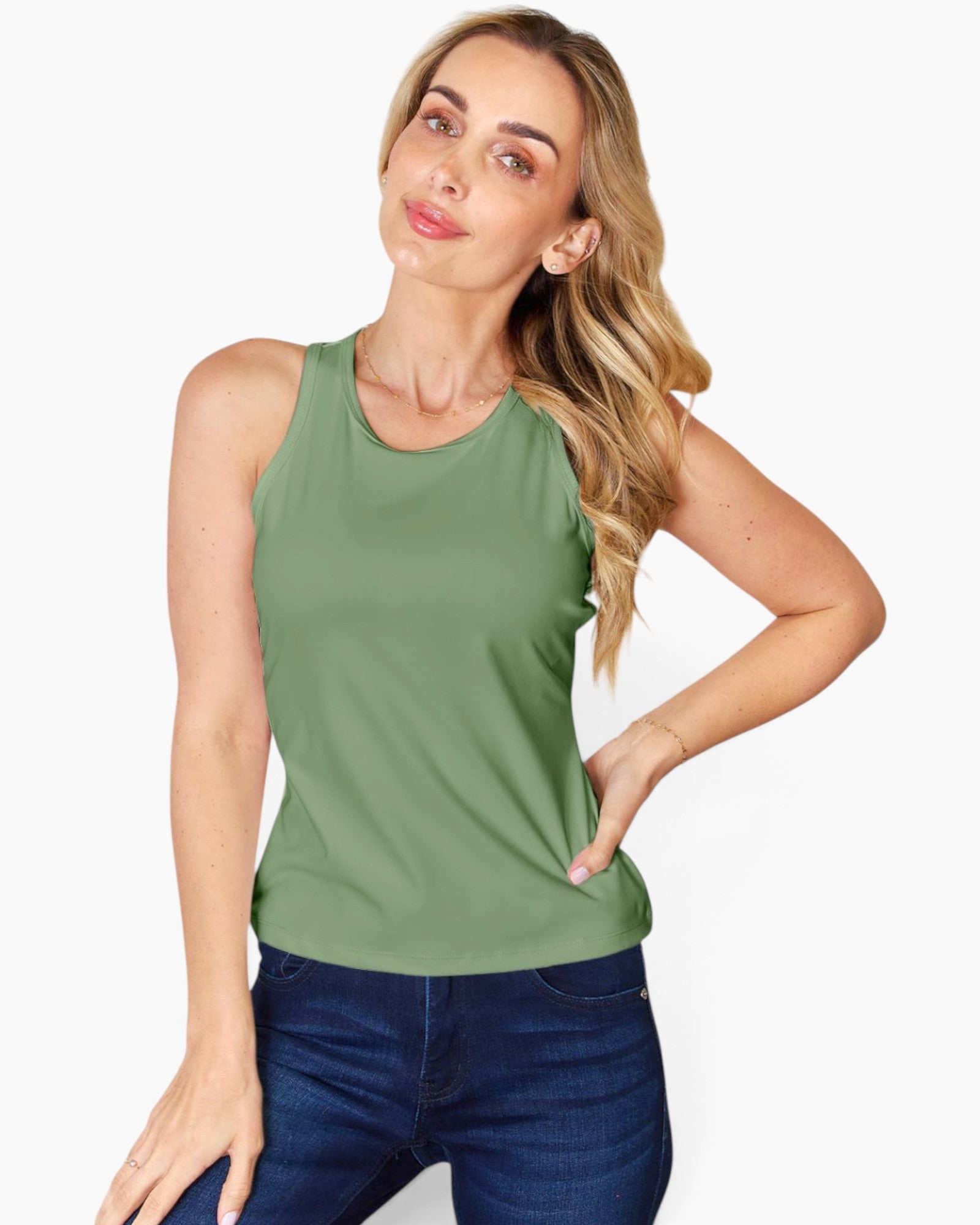 A woman modeling a sleeveless green tank top paired with dark blue jeans, posing against a clean white background.