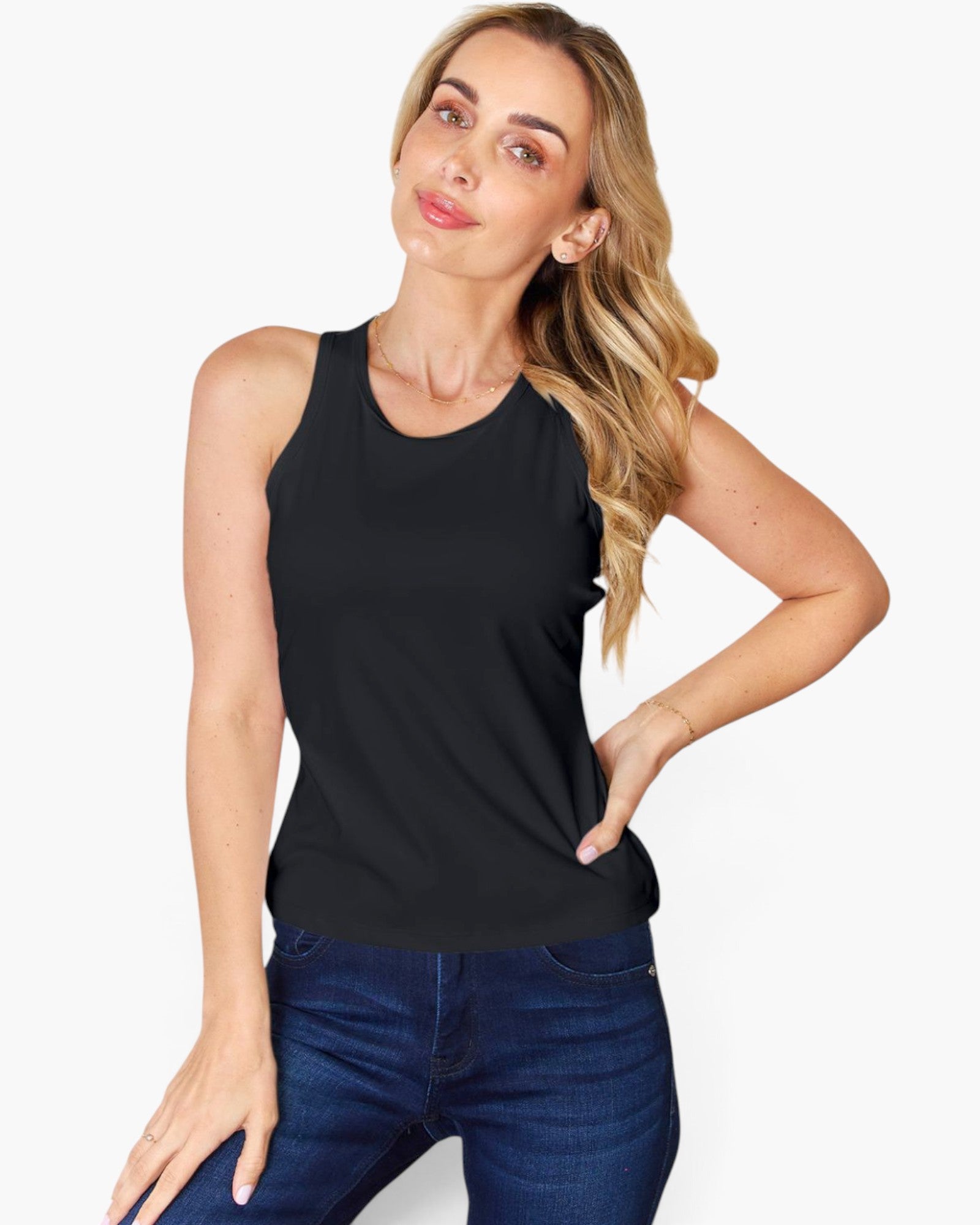 A woman modeling a sleeveless black tank top with blue jeans against a plain light gray background.