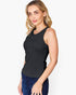 A woman modeling a black sleeveless tank top with a small gold ring detail at the neckline, paired with dark blue jeans, against a plain white background.