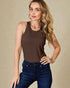 Woman wearing a brown tank top and blue jeans against a beige background