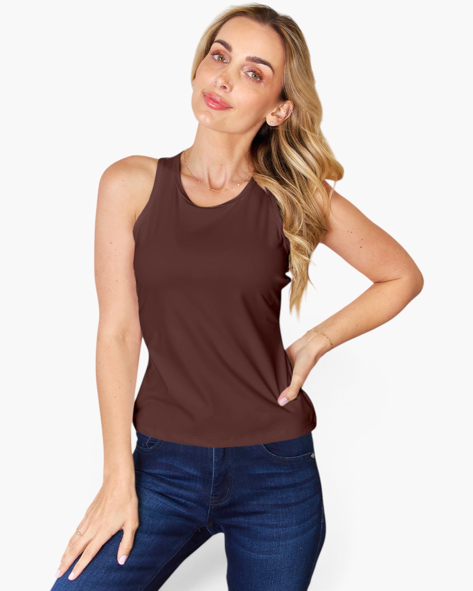 A woman modeling a sleeveless scoop-neck tank top in dark brown, paired with blue jeans, against a plain white studio background.
