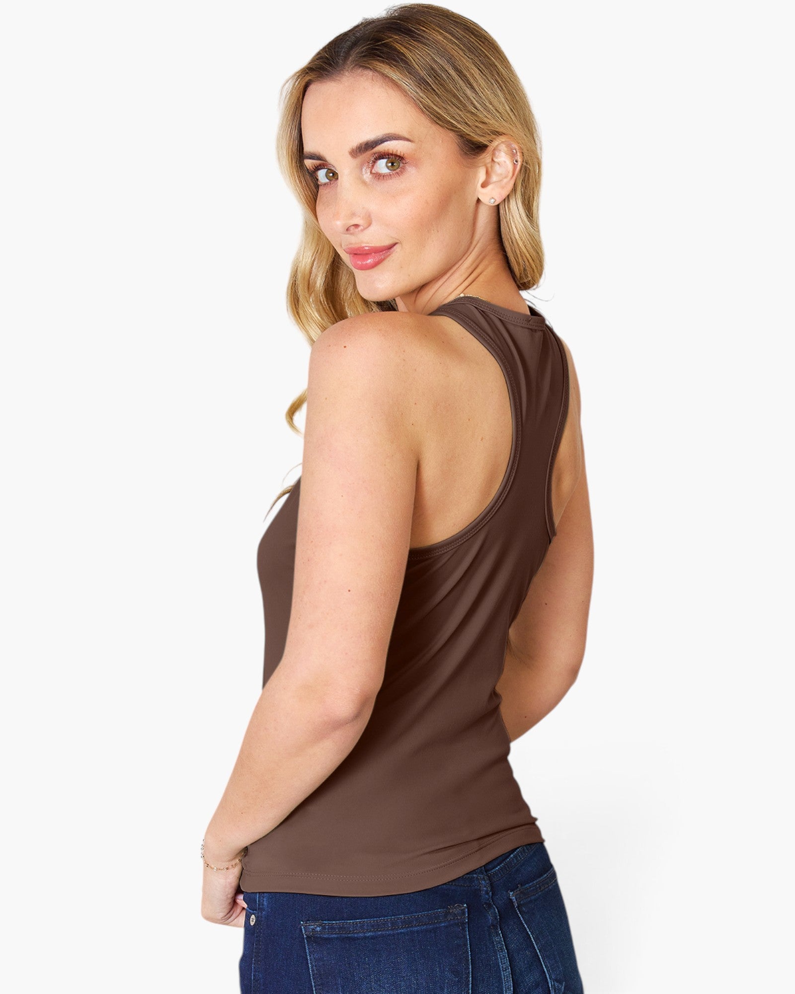 A woman wearing a brown sleeveless racerback tank top and blue jeans, shown from a three-quarters back view against a plain white studio background.