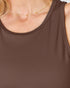 Close-up of a woman wearing a brown sleeveless top and a delicate gold necklace.