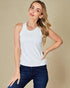 Woman wearing a white sleeveless top and blue jeans on a beige background