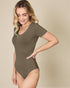 Woman wearing a green bodysuit against a beige background
