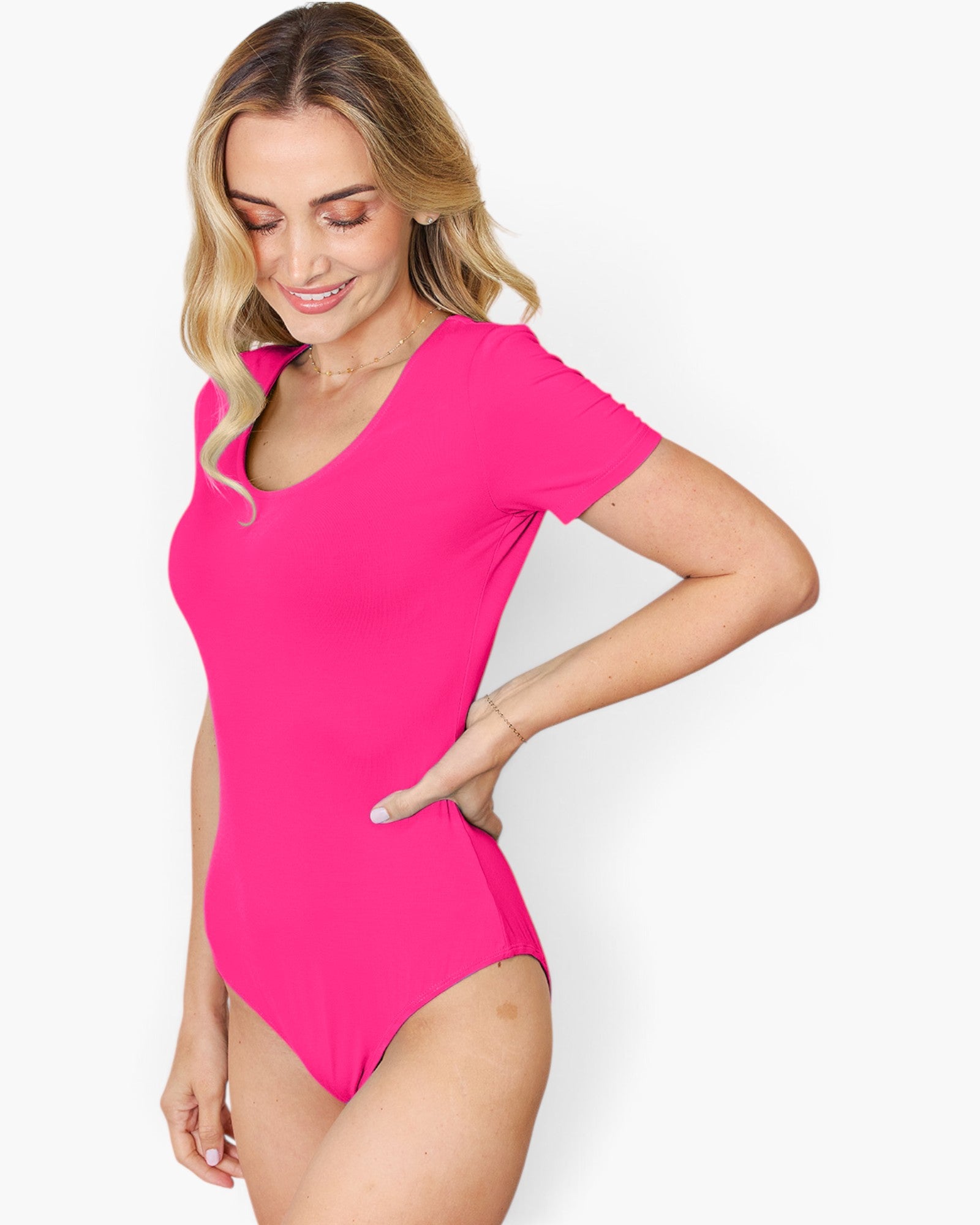 A woman modeling a bright pink short-sleeve one-piece swimsuit against a clean white background.