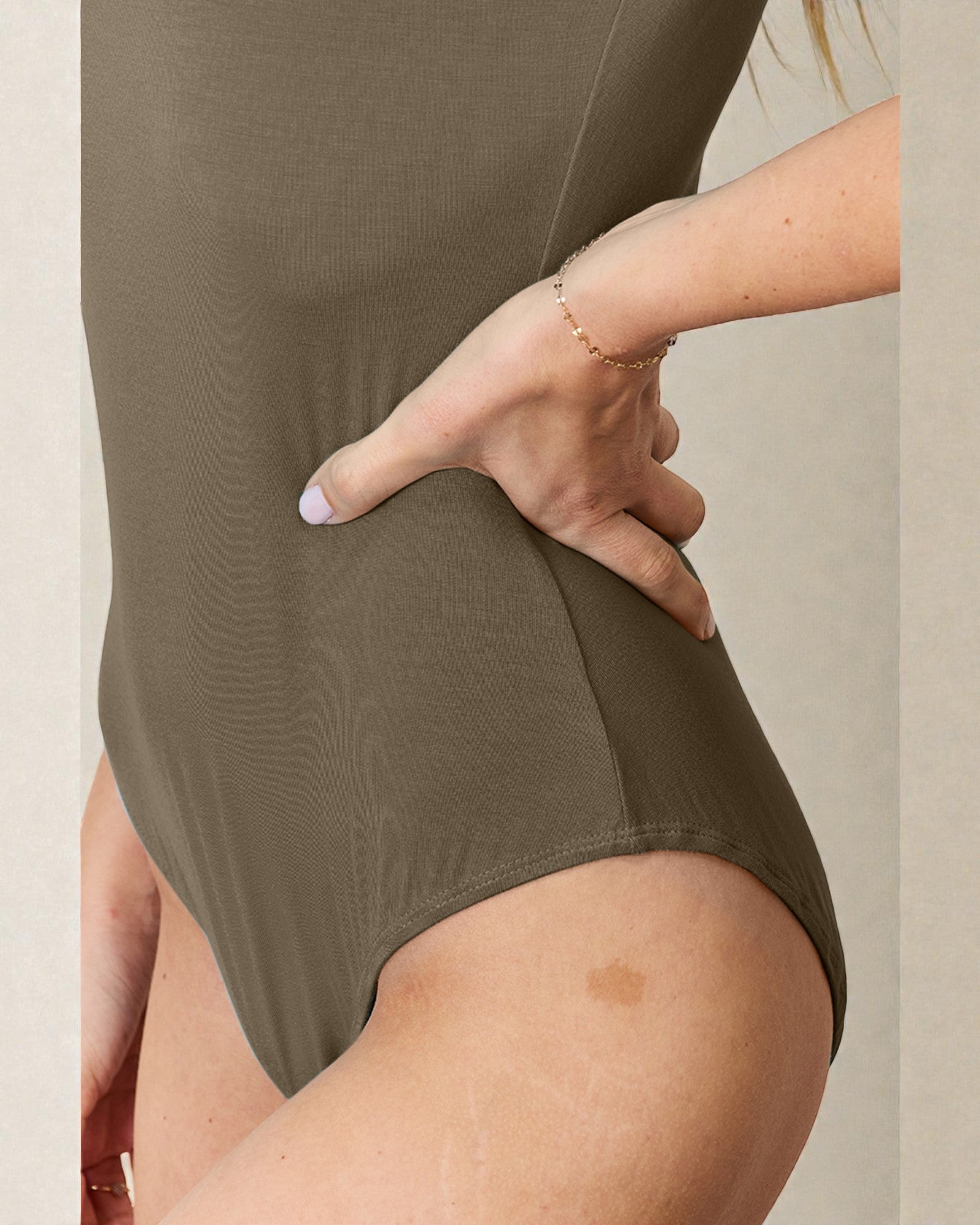 Person wearing a green swimsuit with a neutral background