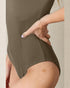 Person wearing a green swimsuit with a neutral background