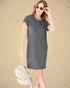 Woman wearing a gray t-shirt dress with sunglasses and a backpack on a beige background