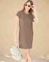 Woman wearing a brown dress holding sunglasses and a backpack against a beige background
