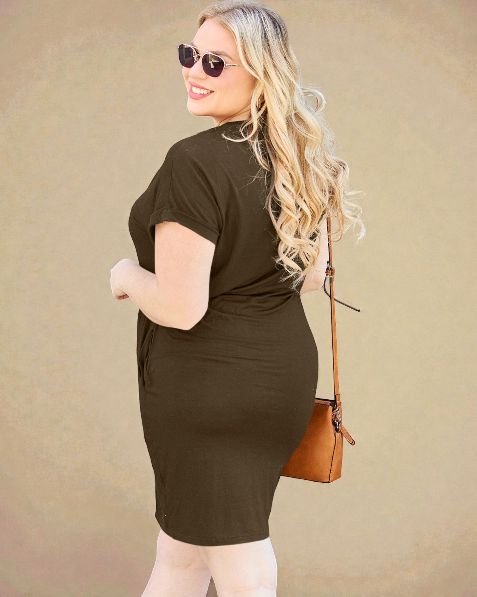 Woman wearing a brown dress with sunglasses and a handbag against a beige background