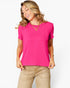 A woman wearing a bright pink short-sleeve crewneck t-shirt and beige pants, standing against a light gray studio background.