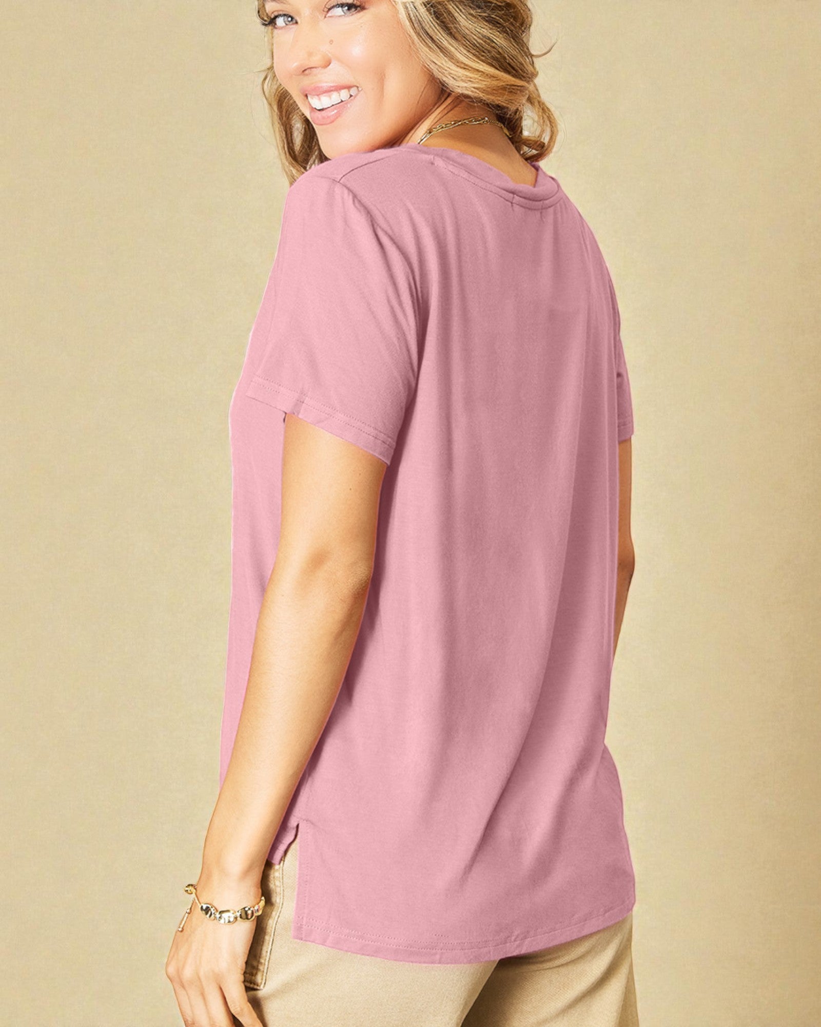 Woman wearing a pink t-shirt against a beige background