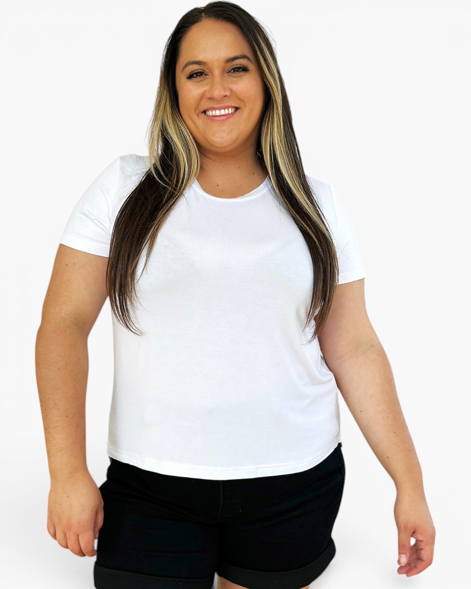 A woman modeling a plain white short-sleeve crewneck t-shirt paired with black shorts, set against a solid light gray background.