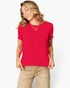 A woman wearing a bright red short-sleeve crewneck top and beige pants, posing against a light gray studio background.