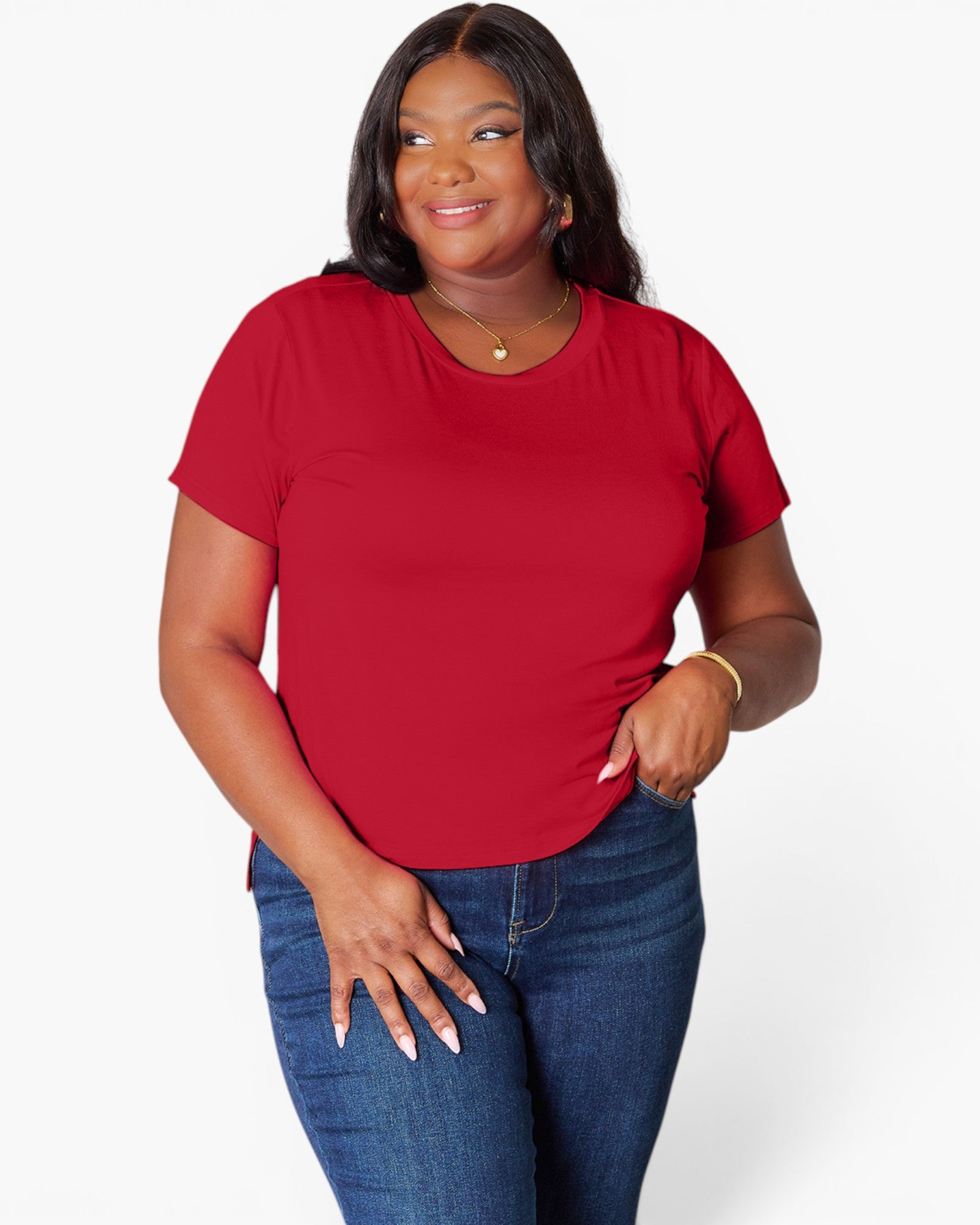 A woman modeling a bright red short-sleeve crewneck t-shirt paired with blue jeans, photographed against a clean white studio background.