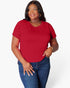 A woman modeling a bright red short-sleeve crewneck t-shirt paired with blue jeans, photographed against a clean white studio background.