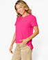 A woman wearing a bright pink short-sleeve t-shirt with a side tie detail and beige cargo pants, posing against a light gray studio background.