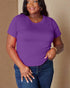 Woman wearing a purple t-shirt and blue jeans against a beige background