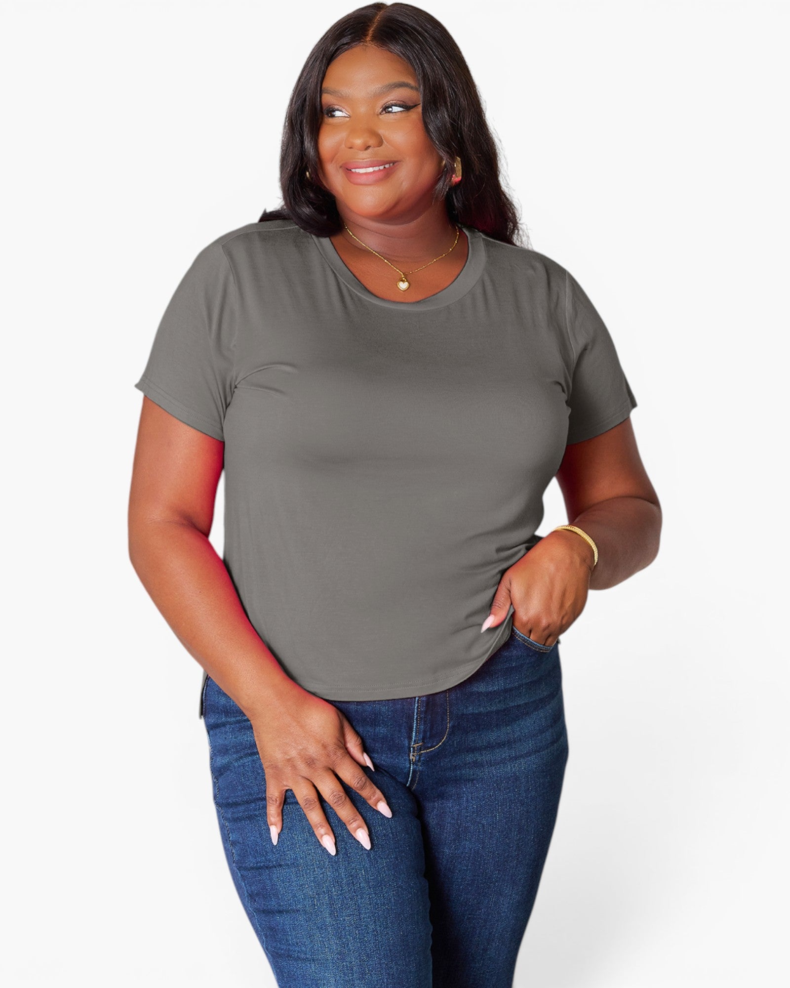 A woman modeling a short-sleeve crewneck t-shirt in a solid gray color, paired with blue jeans, against a plain white studio background.