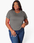 A woman modeling a short-sleeve crewneck t-shirt in a solid gray color, paired with blue jeans, against a plain white studio background.