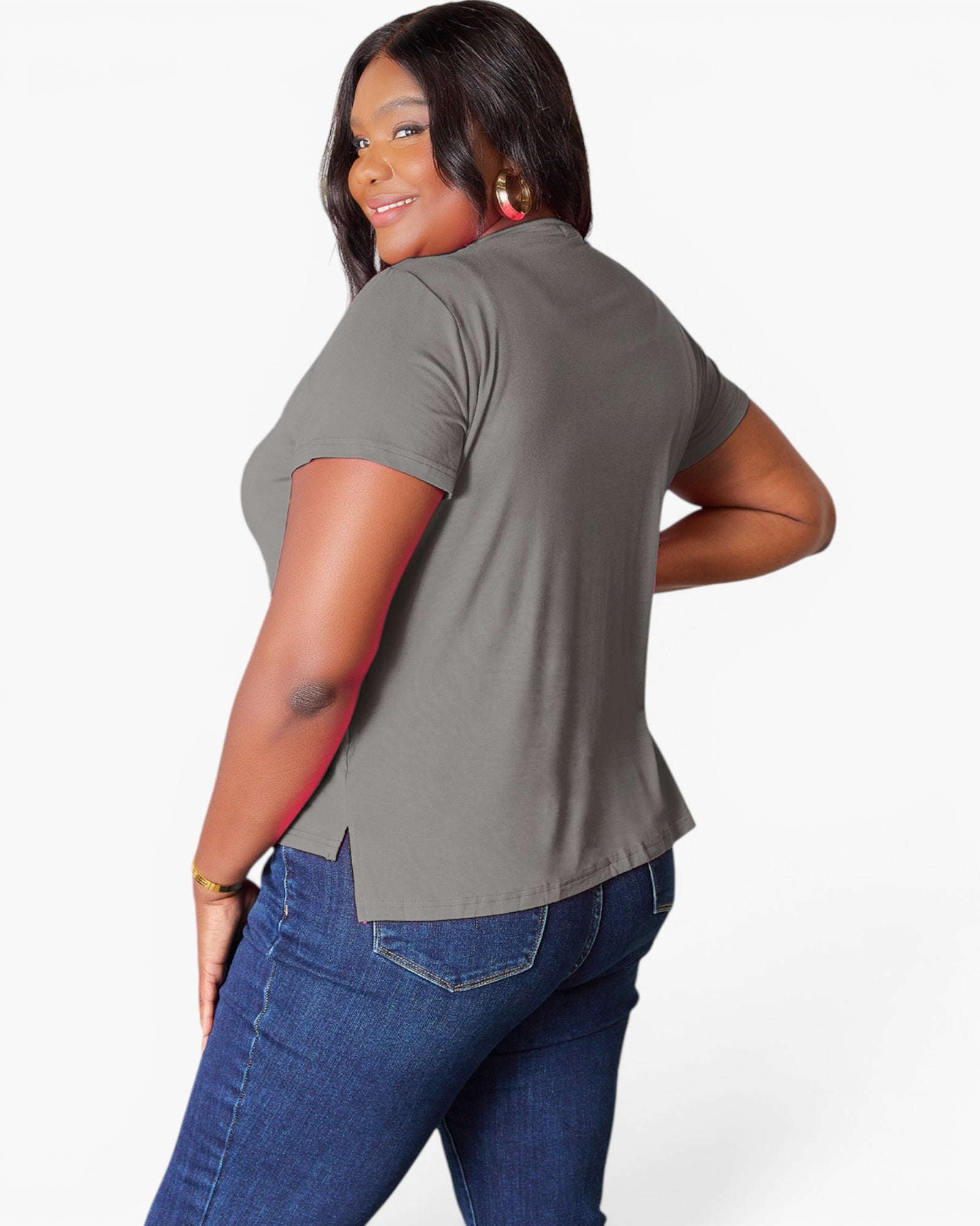 A woman modeling a short-sleeve gray t-shirt from the back, paired with blue jeans, against a plain white studio background.
