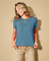 Woman wearing a blue t-shirt and beige pants against a beige background