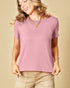 Woman wearing a pink t-shirt and beige pants against a beige background