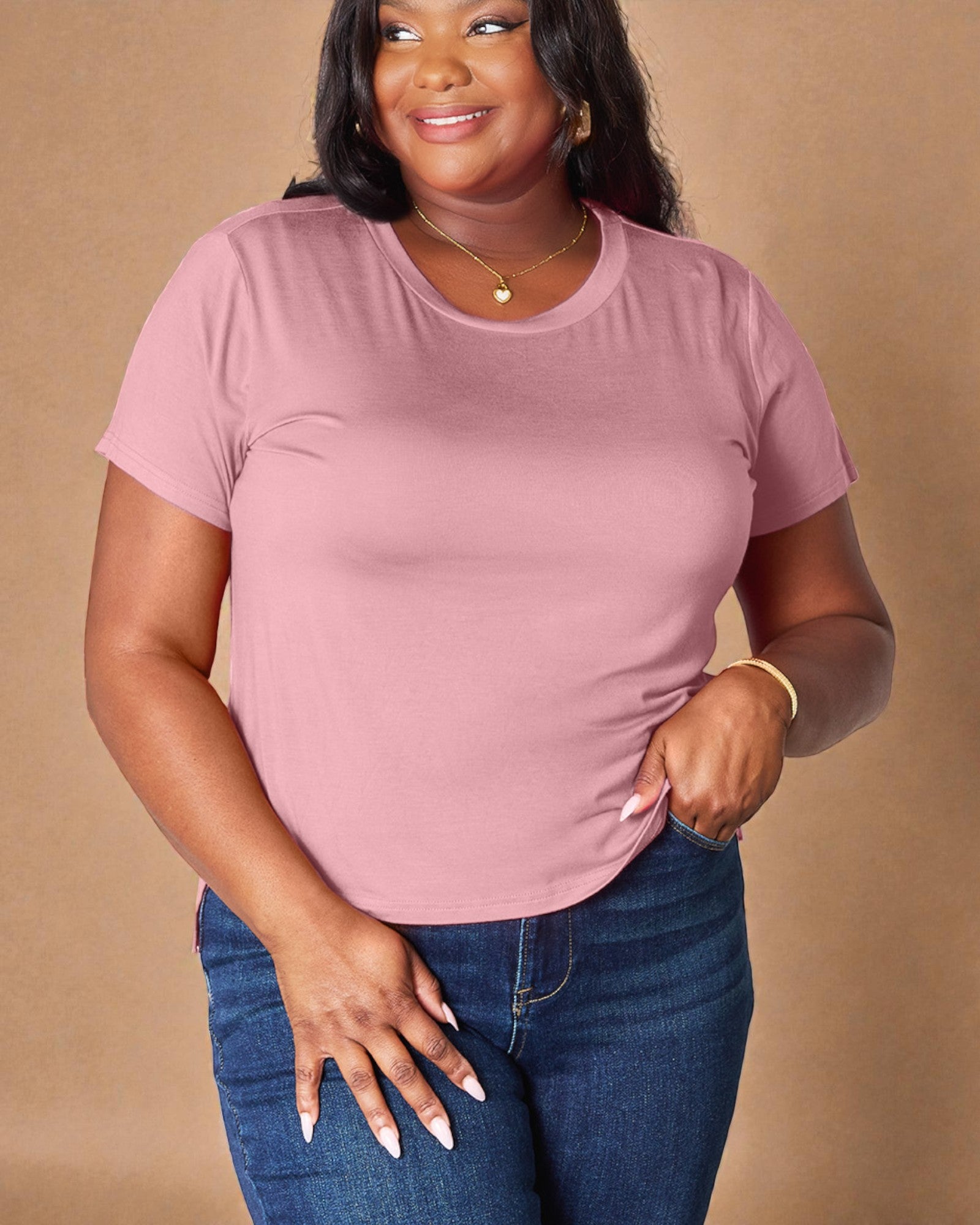 Woman wearing a pink t-shirt and blue jeans against a beige background