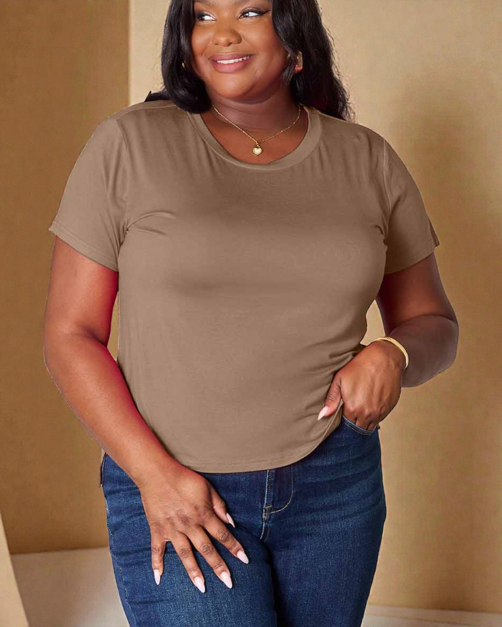 Woman wearing a brown t-shirt and blue jeans against a beige background