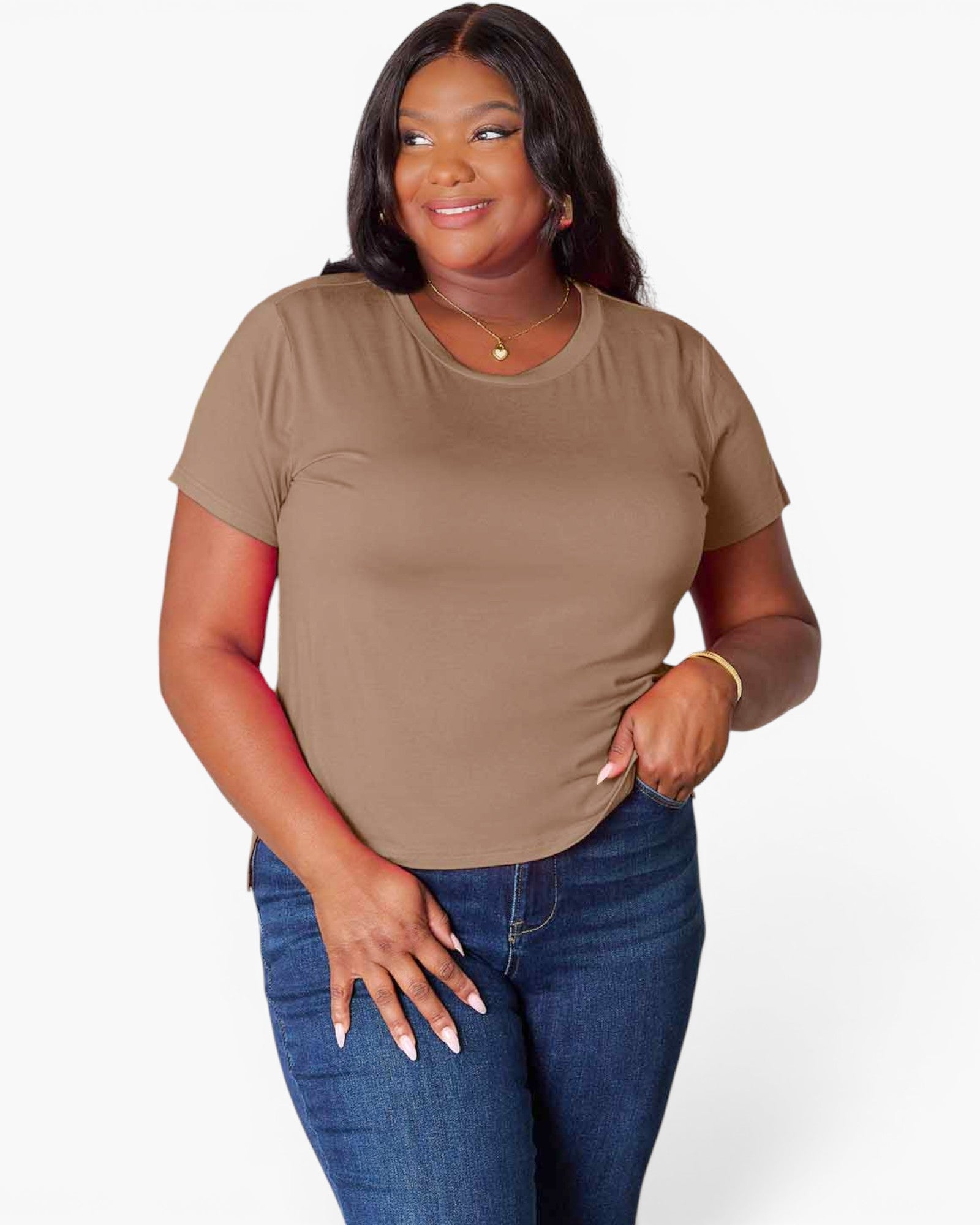 A woman modeling a short-sleeve crewneck t-shirt in a solid taupe-brown color, paired with blue jeans, against a clean white studio background.