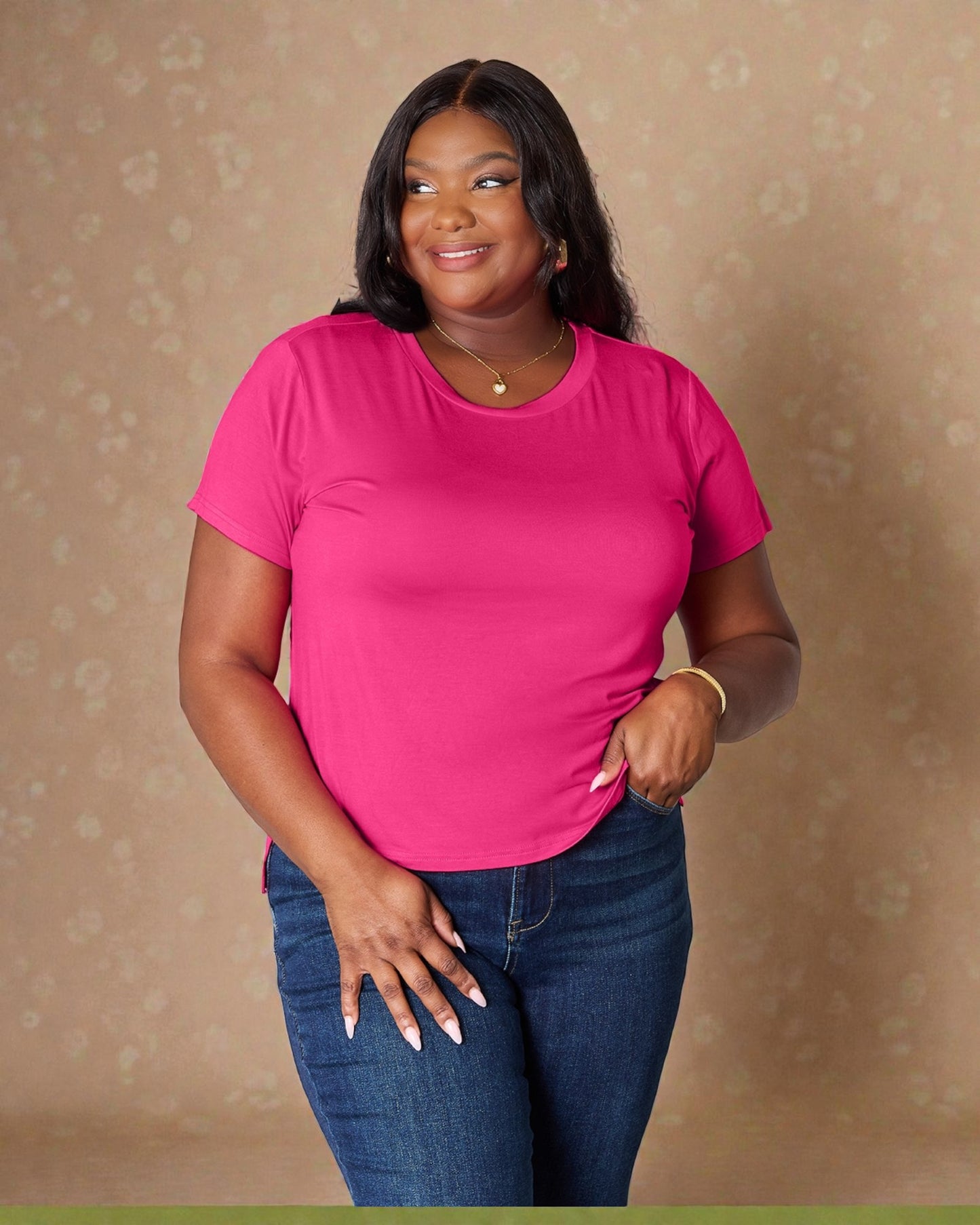 Woman wearing a bright pink t-shirt and blue jeans against a beige background